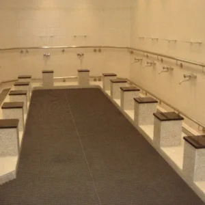 A mosque interior with blue ablution mats designed for prayer rows adorned with gold and white geometric patterns